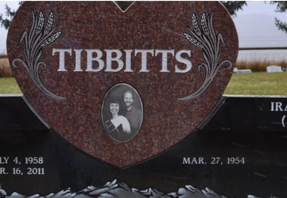 A heart-shaped memorial in red granite with an oval porcelain photograph inlaid at its center.