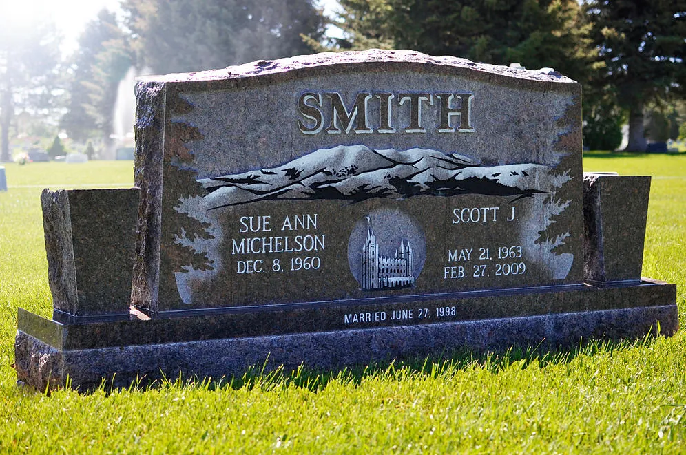 A companion upright monument in dark granite carrying a surname above two sets of names and dates.
